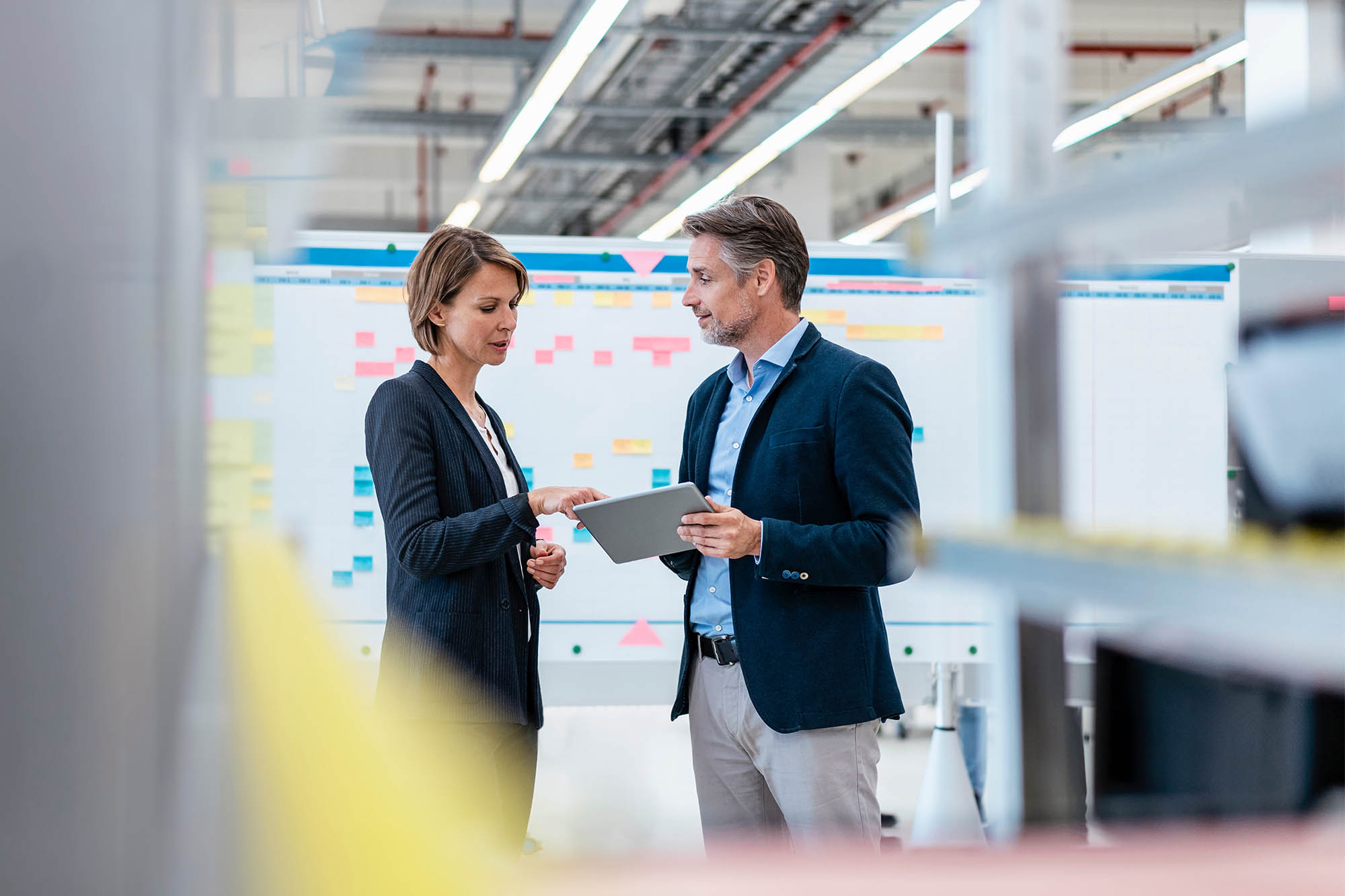 Businessman and businesswoman talking in a factory hall